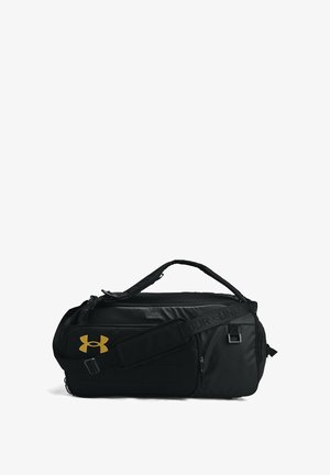 Black duffel bag made of durable fabric. Features a prominent gold logo, adjustable strap, side zipper pocket, and textured handles.