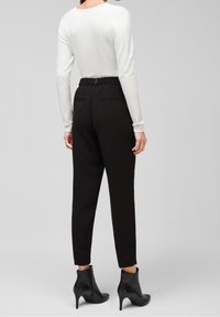 Vit långärmad topp i kombination med svarta smala byxor, med dragsko i midjan och sidofickor, kompletterat med svarta ankelboots.