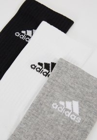 Kolme paari sokke mustas, valges ja hallis. Igaühel on sooniline tekstuur ja Adidas logo kontrastsetes värvides.