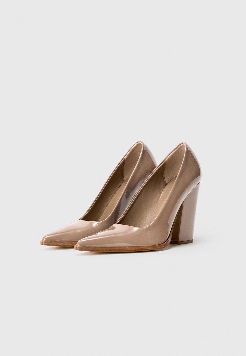 Escarpins à talon haut en cuir verni nude avec un bout pointu et un talon épais. Texture lisse avec une finition brillante.