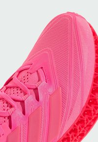 Scarpa sportiva di un brillante colore rosa con tomaia testurizzata, chiusura con lacci e suola decorata con un distintivo design a rete.
