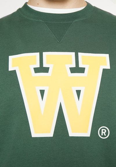 Grüne Sweatshirt mit einem großen gelben und weißen "W"-Logo in der Mitte, mit Rundhalsausschnitt und geripptem Material.