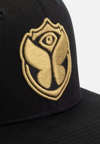 Zwarte pet met een geborduurd gouden logo met een vlinder- en oogontwerp, met gedetailleerde stiksels en een platte rand.