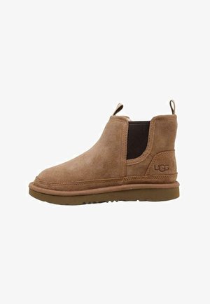 Botas de tobillo de ante marrón con punta redonda, paneles laterales elásticos y suela de goma color beige. Cuentan con una pestaña trasera para tirar y un logotipo grabado en el lateral.