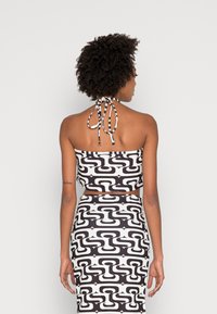 Conjunto bicolor em preto e branco, composto por um top cropped tipo halter com laço nas costas e uma saia justa combinando. Tecido suave e elástico.