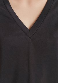 Zwarte V-hals T-shirt met een gladde textuur, voorzien van een nette naad bij de halslijn en een aansluitend ontwerp dat geschikt is voor casual kleding.