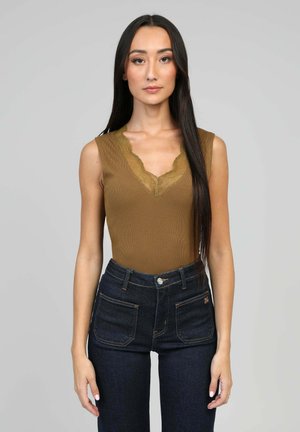 Débardeur en maille marron avec un décolleté en dentelle festonnée, associé à un jean en denim foncé taille haute avec des coutures contrastées et des poches.