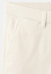 Sztruksowe spodnie w kolorze kremowym o pionowej prążkowanej fakturze, z płaskim paskiem w talii i bocznymi kieszeniami. Szwy z kontrastowym przeszyciem.