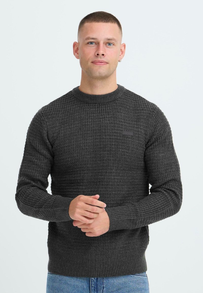 Mørkegrå strikket sweater med et struktureret mønster, rund hals og ribbede manchetter. Lille logo detalje på brystet. Sammen med denim jeans.