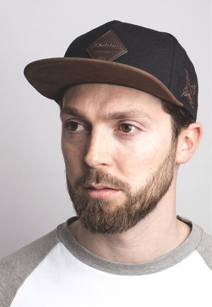 Black cap with a brown suede visor, featuring a diamond-shaped leather patch on the front and a subtle embroidered design on the side.