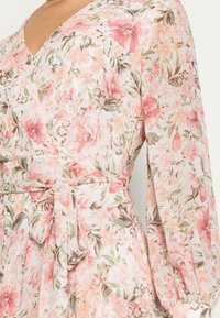 Robe à motif floral dans des tons pastel de rose et vert, dotée d'un col en V, de manches longues et d'une ceinture à la taille pour plus de détail.