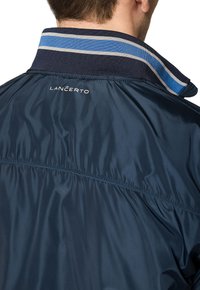 Granatowa, lekka kurtka nylonowa z paskowanym kołnierzem w niebiesko-szare akcenty. Logo "LANCERTO" wyświetlone z tyłu.