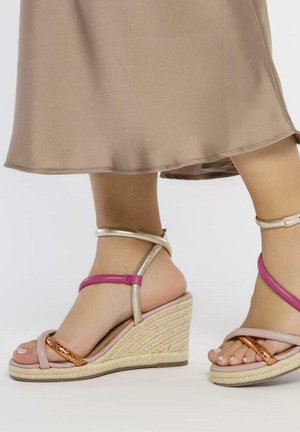 Sandalias de cuña con una base de yute trenzado, tiras rosas y doradas, y una tira de acento naranja, mostrando un diseño multicolor.