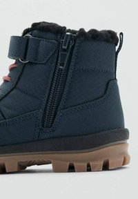 Tmavomodré členkové topánky s textúrovaným povrchom, bočným zipsom, ružovými šnúrkami a gumovou podrážkou s protišmykovými vzormi. Umelá kožušina na golieri.