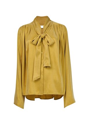 Blusa de manga larga mostaza con una textura suave, que presenta un cuello con lazo, botones frontales y hombros con pliegues. Diseño de dobladillo curvado.