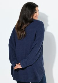 Marinblå oversized tröja med en strukturerad stickning, droppade axlar och ribbade ärmslut, med en lös passform och sidsprund för komfort.