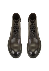 Bottes de cheville en cuir marron foncé avec une texture lisse, présentant un design à lacets et une fermeture éclair sur le côté. Bout arrondi et semelle en caoutchouc robuste.