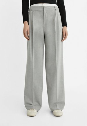 Pantalons larges gris clair avec des plis, une taille élastique blanche et une fermeture à bouton. Tissu doux avec une texture lisse.