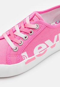 Baskets en textile rose avec une tige en maille, dotées de lacets ton sur ton, d'œillets en argent et d'une semelle en caoutchouc blanc avec un marquage imprimé sur le côté.