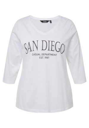 Camiseta de algodón blanca de manga larga con cuello en V. Lleva impreso "SAN DIEGO CASUAL DEPARTMENT EST. 1987" en negro. Textura suave.