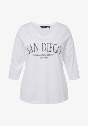 Camiseta de algodón blanca de manga larga con cuello en V. Lleva impreso "SAN DIEGO CASUAL DEPARTMENT EST. 1987" en negro. Textura suave.