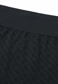 Mustat urheilushortsit ribbireunuksella, joissa on teksturoitu kuvio kankaan pinnalla. Sileä pinta hienovaraisilla yksityiskohdilla.