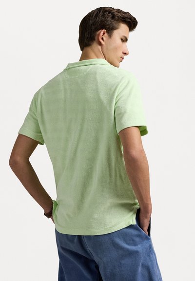 Korte mouwen polo-shirt in lichtgroen terry stof, met een kraag en een relaxte pasvorm, voorzien van een zijsplit aan de onderkant.