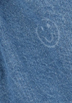 Denimstof in lichtblauw met een subtiele visgraatstructuur en een vaag smiley-gezicht patroon. Zachte, geweven textuur, typisch voor jeansmateriaal.