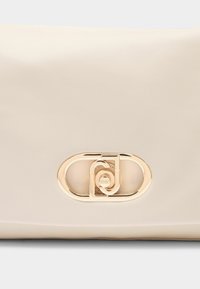 Beige väska i syntetiskt läder med en slät yta, med en guldfärgad oval spänndetalj på framsidan. Rektangulär form, minimalistisk design.