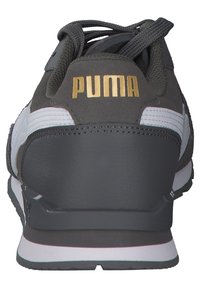 Zadní pohled na černobílé tenisky Puma se zlatým logem a černými tkaničkami, zobrazující detaily paty a podrážky.