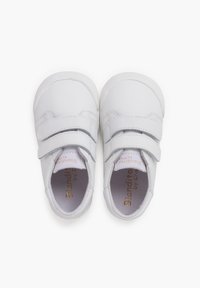 Sneakers bianchi con una finitura in pelle liscia, doppie cinghie a strappo, punte arrotondate e suole in gomma testurizzata. Nome del marchio visibile all'interno.
