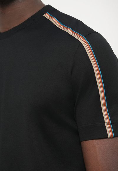 Čierne tričko s krátkymi rukávmi so vzorom viacfarebného diagonálneho pruhu pozdĺž ramena, vyrobené z mäkkého materiálu.