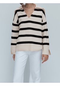 Gestreepte trui in beige en zwart met een V-hals en kraag, gemaakt van een zachte stof, met zijsplitten en een ontspannen pasvorm.