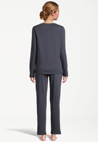 Kolgrå långärmad topp och matchande byxor tillverkade av mjukt, lätt material. Avslappnad passform med rak skärning på benen och rundad nederkant.