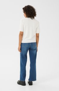 Hvid, kortærmet striktop parret med højtaljede, lige ben blå jeans. Modellen har sorte platform sko på, set bagfra.