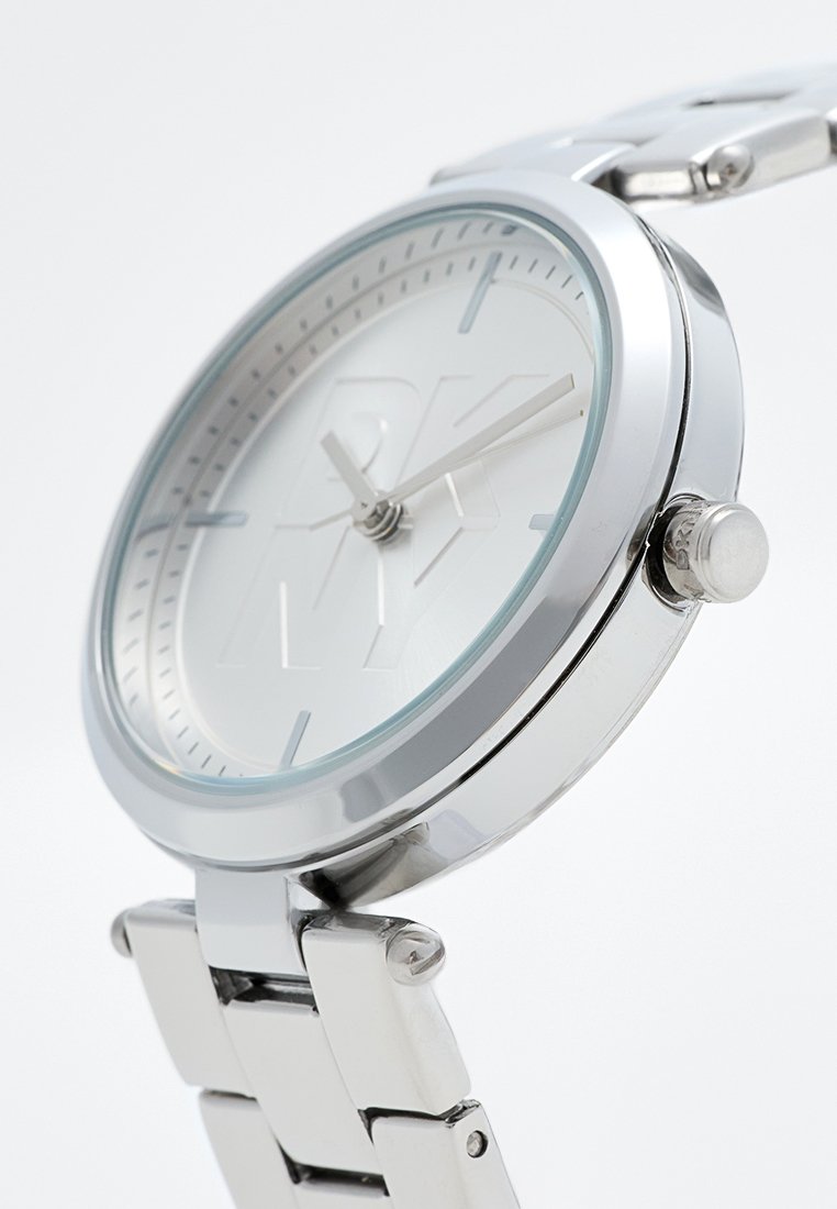 Montre en argent avec un boîtier rond, un cadran blanc avec des initiales en relief et un bracelet en acier inoxydable à maillons. Remarquable par son design minimaliste.