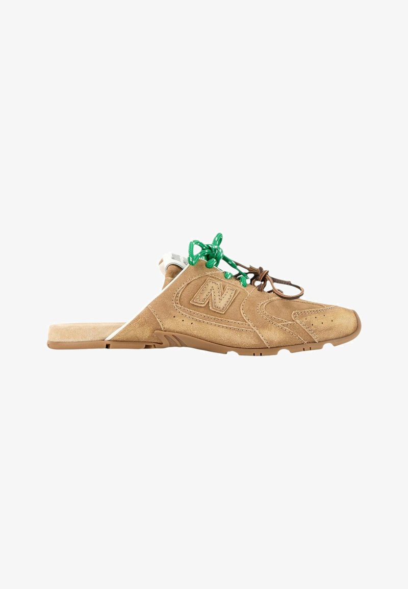 Chaussure en daim marron à enfiler avec des lacets verts et marron, semelle en caoutchouc plate et un logo "N" cousu sur le côté.