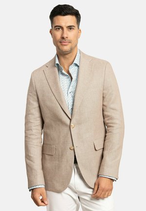 Blazer de lino beige con dos bolsillos frontales y dos botones. Debajo, una camisa de estampado floral azul claro. Pantalones blancos visibles.