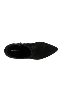 Bottines noires à talon avec un orteil pointu, texture en suède, fermeture éclair sur le côté et intérieur de marque. Design simple sans motifs ni accents visibles.