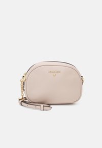 Bolso bandolera de cuero beige con forma redondeada, herrajes dorados y correa ajustable. Presenta un logo en relieve y cierre de cremallera.