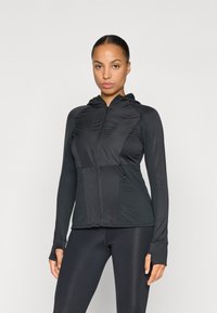 Zwarte zip-up jas met een capuchon en textuurpanelen. Beschikt over duimgaten, afsluitbare zakken en een gladde afwerking op de mouwen.
