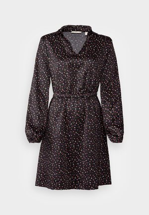 Vestido negro de manga larga, con cuello con solapa y cintura elástica. Presenta un patrón de estrellas coloridas por todo el tejido. Textura sedosa.