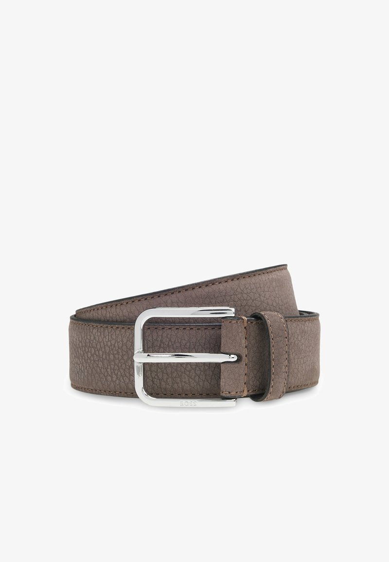 Bruine leren riem met textuur, voorzien van een zilveren metalen gesp en zichtbare stiksels, opgerold tegen een witte achtergrond.
