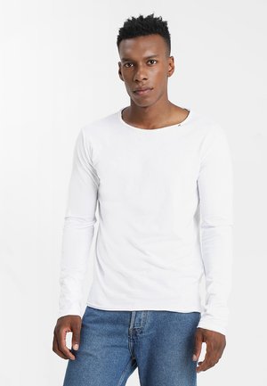 T-shirt bianco a maniche lunghe con scollatura rotonda, realizzata in cotone. Il tessuto ha una consistenza liscia, arricchita da un design minimalista.