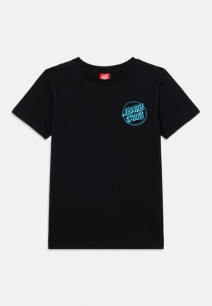 Melna īsroku T-krekls ar mazu apaļu tirkīza krāsas "Santa Cruz" logotipu uz kreisās krūtīm un sarkanu apkakles etiķeti.