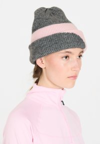 Harmaa neulepipo, jossa on vaaleanpunainen vaakasuora raita, ribbikuviointi ja kapea huippu. Yhdistetty vetoketjulliseen vaaleanpunaiseen yläosaan.