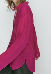 Magenta sheer blouse with a high collar, button front, long sleeves, and curved hemline. Lightweight fabric with a smooth texture.