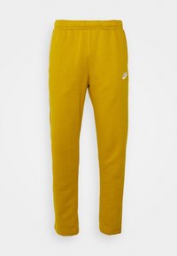 Žluté bavlněné tepláky s elastickým páskem, zúženými nohavicemi a bílým logem Nike na přední straně. Hladká textura, neformální design.