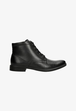 Bottines noires en cuir avec un bout arrondi, six œillets pour les lacets, des coutures décoratives et un petit talon en caoutchouc. Fini lisse et design épuré.