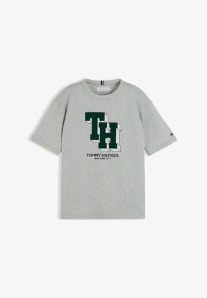 Lysegrå t-shirt med korte ærmer med grønne 3D "TH" bogstaver og "Tommy Hilfiger New York City" tekst på forsiden.
